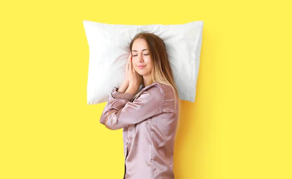 Slapende jonge vrouw met kussen op kleur achtergrond — Stockfoto