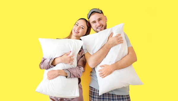 Молодая пара с подушками на цветном фоне — стоковое фото
