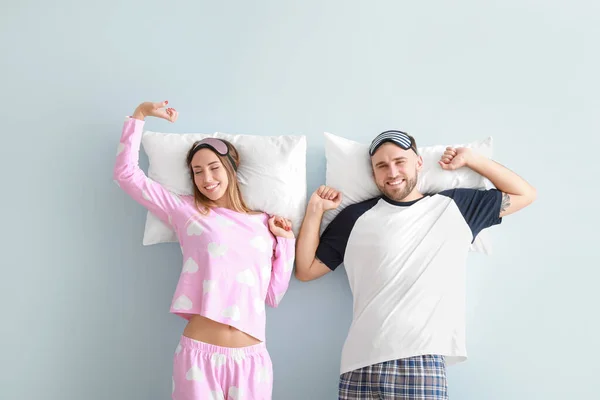 Ospalý mladý pár s polštáři na barevném pozadí — Stock fotografie