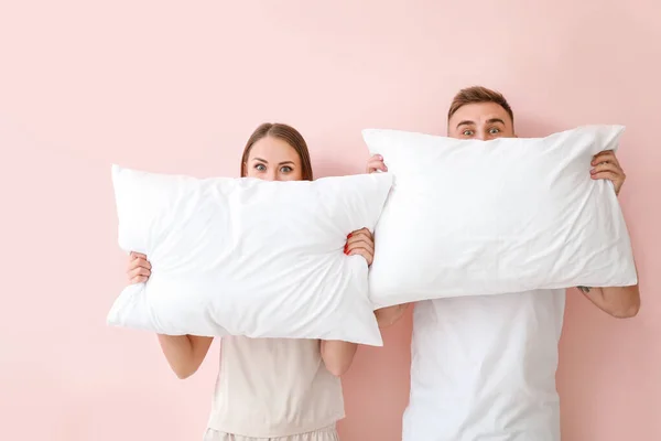 Pareja joven con almohadas sobre fondo de color —  Fotos de Stock