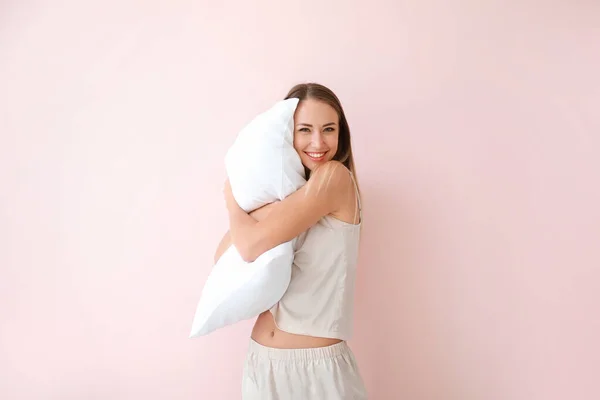 Junge Frau mit Kissen auf farbigem Hintergrund — Stockfoto
