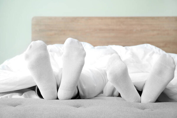 Feet of young couple sleeping in bed