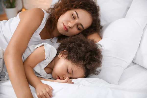 Liten afro-amerikansk flicka med mamma sover i sängen — Stockfoto