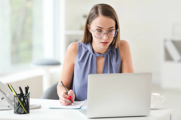Young woman working on laptop in office — Stock Photo, Image