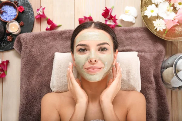 Beautiful young woman with facial mask relaxing in spa salon — Stock Photo, Image
