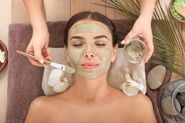 Cosmetologist applying mask onto face of young woman in spa salon — Stock Photo, Image