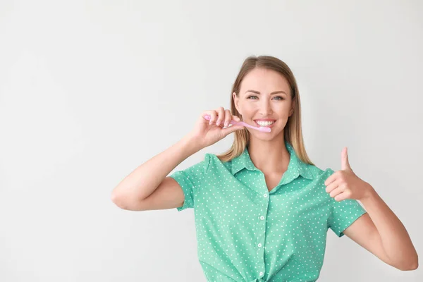 Porträt einer Frau beim Zähneputzen auf hellem Hintergrund — Stockfoto