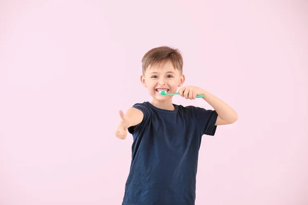 Retrato de niño pequeño cepillándose los dientes sobre fondo de color — Foto de Stock
