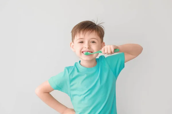 Retrato de menino escovando dentes no fundo claro — Fotografia de Stock