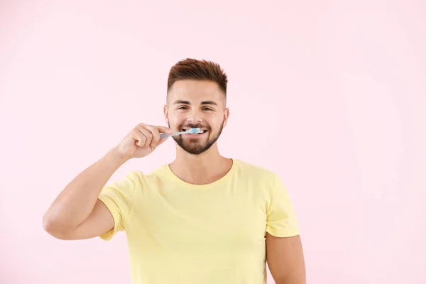 Retrato de homem escovando dentes no fundo de cor — Fotografia de Stock