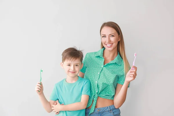 Portret matki i jej synka myjących zęby na jasnym tle — Zdjęcie stockowe