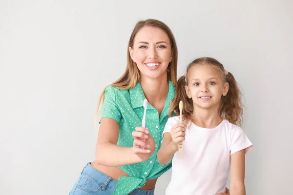 浅色背景下母亲和小女儿刷牙的肖像 — 图库照片