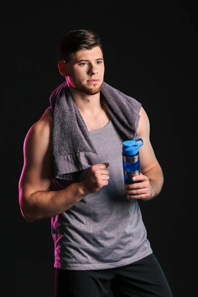 Siyah arka planda bir şişe suyu olan sportif genç bir adam. — Stok fotoğraf