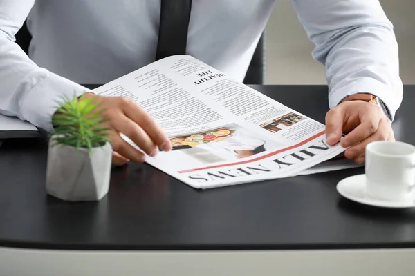Красивый бизнесмен читает газету в офисе, крупным планом — стоковое фото