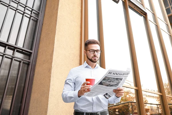 Hombre guapo con periódico y taza de café al aire libre — Foto de Stock