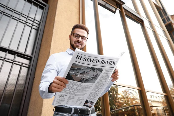 Dışarıda gazetesi olan yakışıklı bir adam.