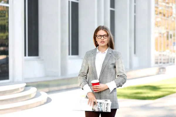 Joven empresaria con periódico y taza de café al aire libre — Foto de Stock