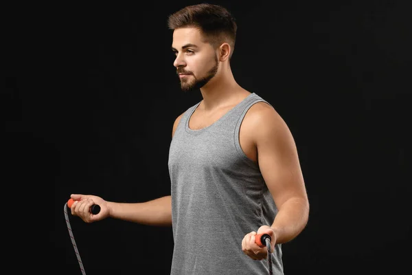 Joven deportivo con cuerda de salto sobre fondo oscuro — Foto de Stock