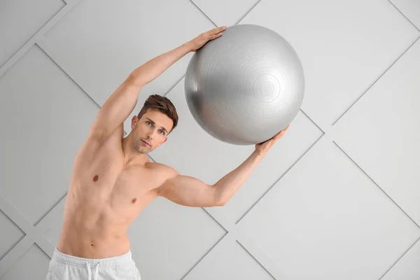 Sporty young man with fitball on light background — Stock Photo, Image
