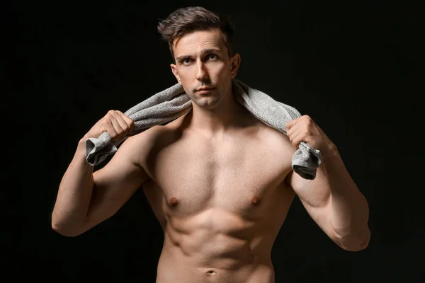 Sporty young man with towel on dark background — Stock Photo, Image