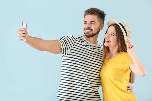 Ritratto di giovane coppia felice scattare selfie su sfondo a colori — Foto Stock