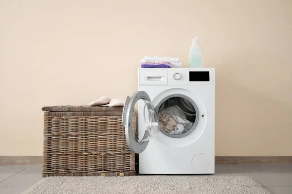 Machine à laver moderne avec buanderie près du mur de couleur — Photo
