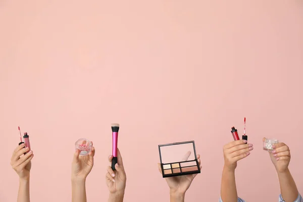 Many hands with decorative cosmetics on color background