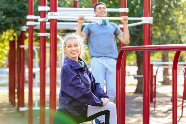 Sporty young couple training on athletic field outdoors — Stock Photo, Image