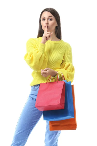Красивая молодая женщина с пакетами для покупок показывает молчание жест на белом фоне — стоковое фото