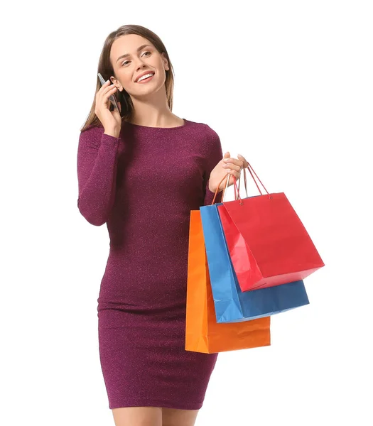 Mulher bonita com sacos de compras falando por telefone no fundo branco — Fotografia de Stock