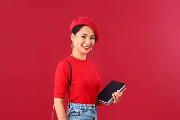 Fashionabla asiatiska kvinna med böcker om färg bakgrund — Stockfoto