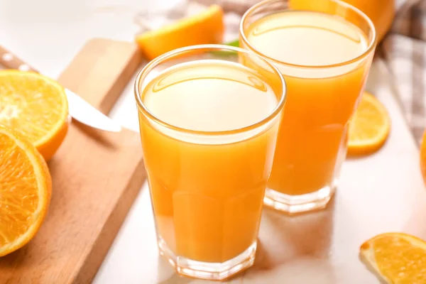 Ποτήρια φρέσκου χυμού πορτοκαλιού σε ελαφρύ τραπέζι — Φωτογραφία Αρχείου