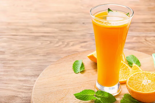 Ποτήρι φρέσκου χυμού πορτοκαλιού σε ξύλινο τραπέζι — Φωτογραφία Αρχείου