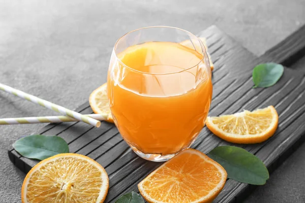 Glass of fresh orange juice on wooden board — Stock Photo, Image