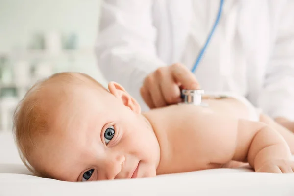Pediatrician examining cute baby in clinic, closeup — Stock Photo, Image
