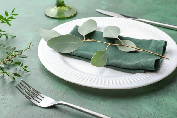 Beautiful table setting with eucalyptus on color background — Stock Photo, Image