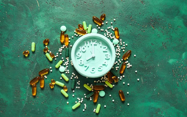 Relógio e muitas pílulas diferentes em fundo de cor — Fotografia de Stock