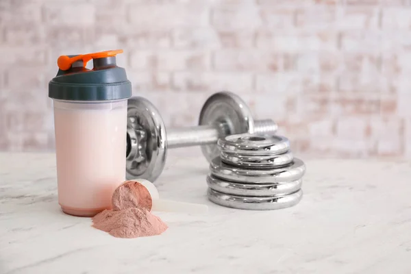 Garrafa de batido de proteína com haltere no fundo claro — Fotografia de Stock