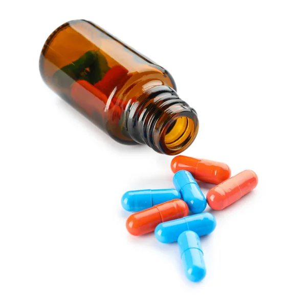 Lahvička s různými pilulky na bílém pozadí — Stock fotografie