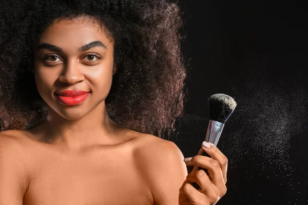 Portret van mooie Afro-Amerikaanse vrouw met make-up borstel op donkere achtergrond — Stockfoto
