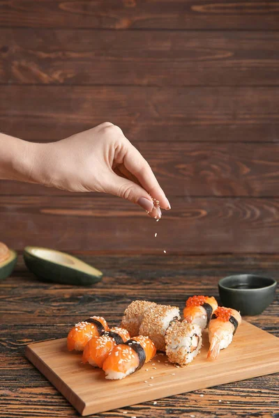 Donna che spruzza sushi saporito con semi di sesamo — Foto Stock