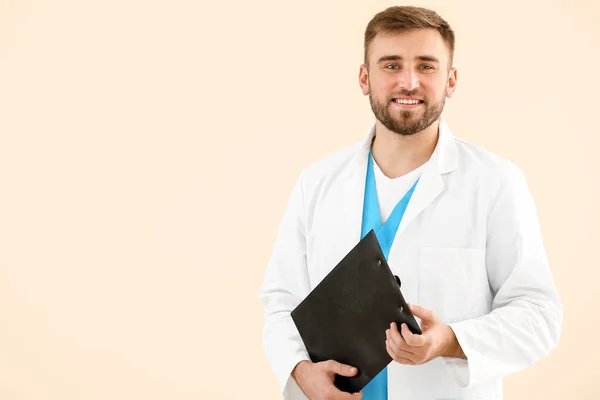 Portret van mannelijke arts met klembord op lichte achtergrond — Stockfoto