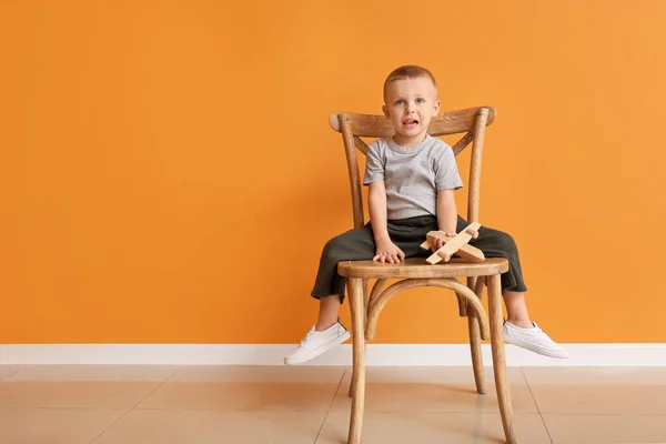 Portré aranyos kisfiú játék ül a széken a színes háttér — Stock Fotó