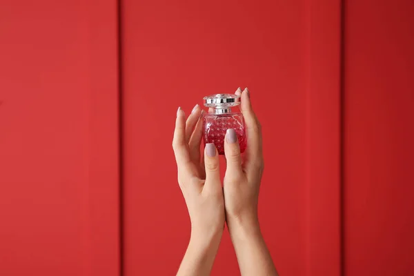女性手与一瓶香水的颜色背景 — 图库照片