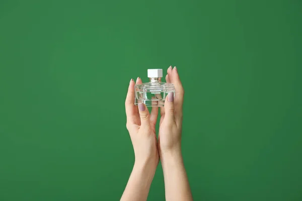 Női kéz üveg parfümöt a színes háttér — Stock Fotó