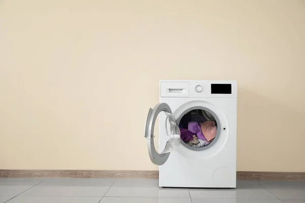 Modern washing machine with laundry near color wall — Stock Photo, Image