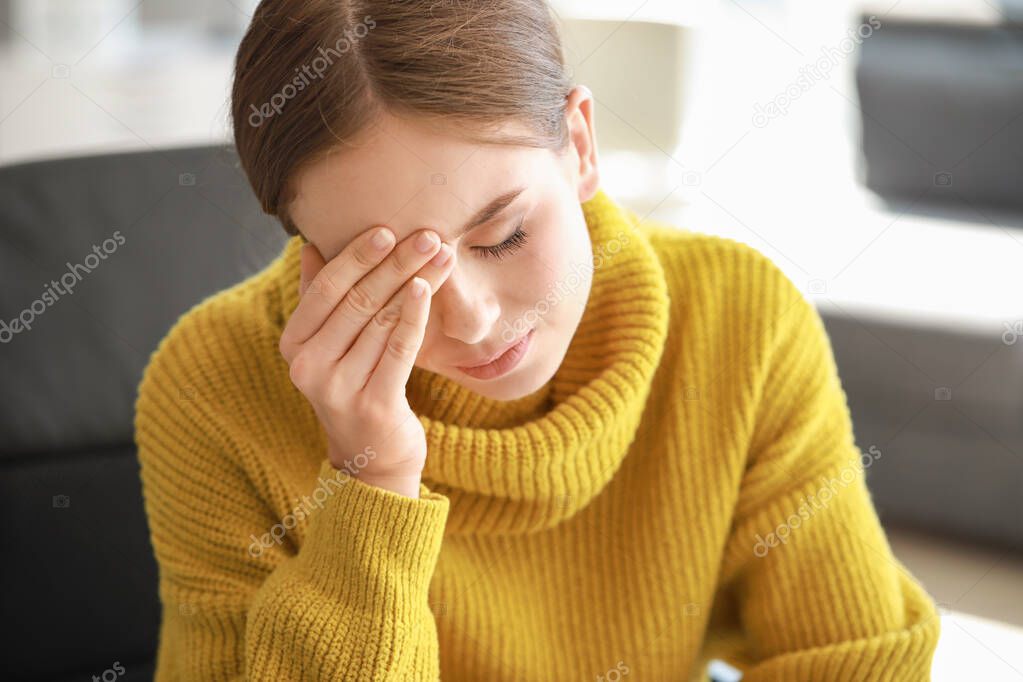 Young woman suffering from headache at home