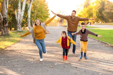 Mutlu aile sonbahar parkında eğleniyor.
