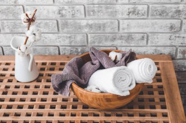 Tuğla duvarın yanındaki tahta kutuda temiz havlularla kase.