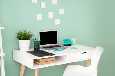 Renk duvarının yanında modern dizüstü bilgisayarı olan rahat bir iş yeri